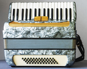 a small mother-of-pearl accordion on a gray background close-up