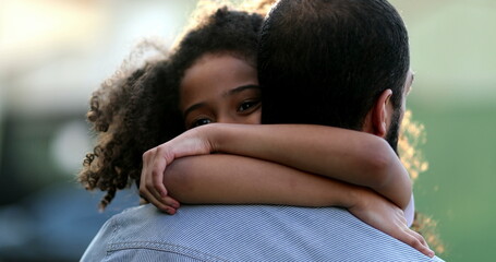 Daughter hugging father outside. Mixed race ethnicity little girl hugs dad