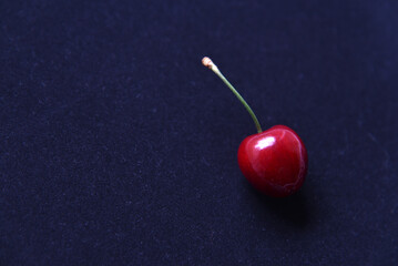 Red juicy cherry berries on a black velvet background.
