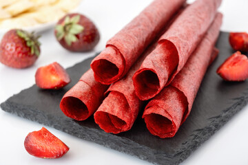 Homemade strawberry fruit leather on black slate closeup. Healthy red berries pastille. Natural vegan snack.