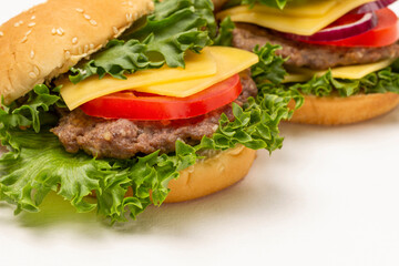 Burger bun on lettuce leaf with cheese and tomatoes.
