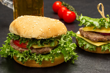 Cheeseburger with greens on bun with sesame seeds.