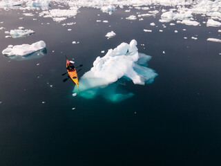 kayak next to a gigantic iceberg in ilulissat greenland outdoor sports kayaking along frozen icebergs in open sea water - obrazy, fototapety, plakaty