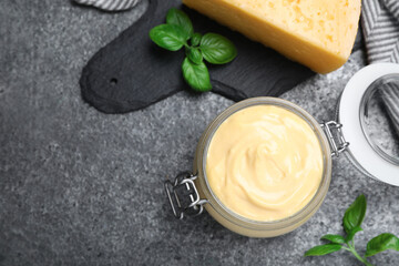 Tasty cheese sauce and basil on grey table, flat lay. Space for text