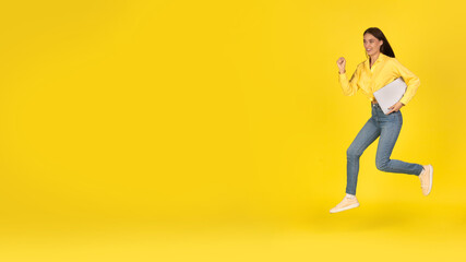 Fototapeta na wymiar Happy Woman Running Holding Laptop Looking Aside Over Yellow Background