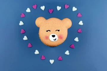 Foto op Canvas Cute macaron in a shape of bear in heart created from small hearts, blue background. Love concept, greeting card © Martina