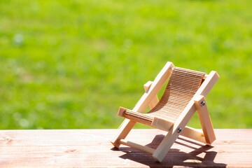 Wooden deck chair on a green summer lawn. Chaise longue for relaxation. Wooden garden furniture on...