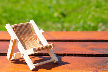 Wooden deck chair on a green summer lawn. Chaise longue for relaxation. Wooden garden furniture on...