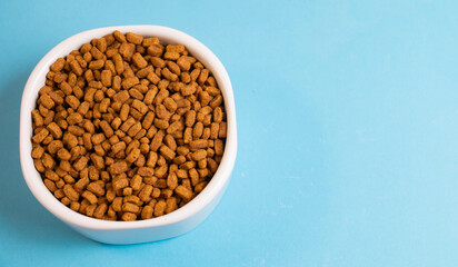 dry food for cats in a white bowl on a blue background, banner