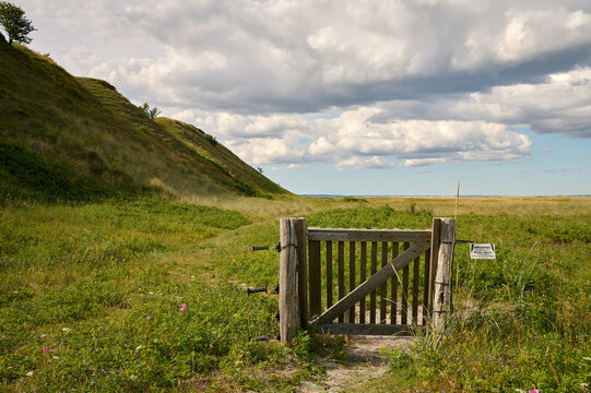 Holztor an einem Zaun vor den H&uuml;geln der Issehoved an der Nordspitze der d&auml;nischen Ostsee Insel Sams&oslash; vor bew&ouml;lktem Himmel