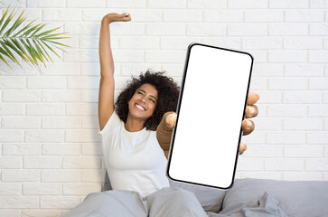 Happy Black Female Holding Big Blank Smartphone And Stretching In Bed