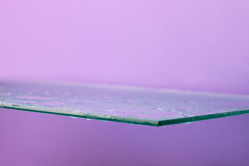 Creative glass podium, empty shelf with water drops, purple background, copy space, looking up.