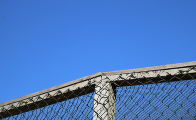 Fototapeta premium Enclosure background showing netted cage against deep blue sky with copy space