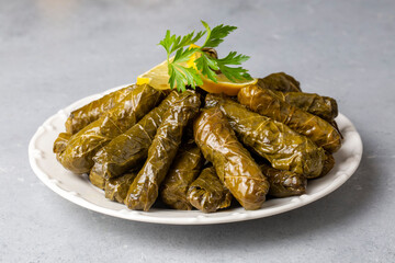 Delicious dolma (sarma) stuffed grape leaves rice, white yogurt sauce. Lebanese dolma sarma on plate. Lebanon turkish greek middle eastern cuisine. (Turkish name; Yaprak sarma)