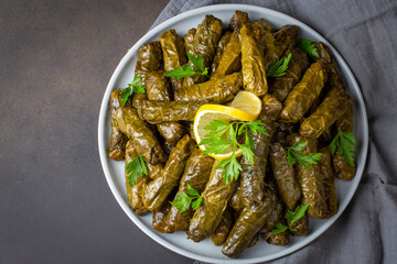 Delicious dolma (sarma) stuffed grape leaves rice, white yogurt sauce. Lebanese dolma sarma on plate. Lebanon turkish greek middle eastern cuisine. (Turkish name; Yaprak sarma)