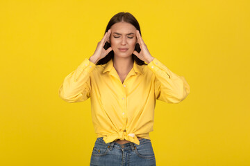 Sick Woman Suffering From Headache Standing On Yellow Background