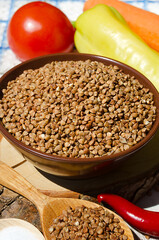 Buckwheat in a bowl, red pepper, carrots and onions on the board.