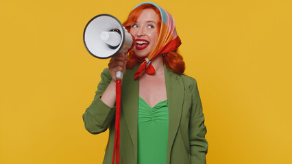 Smiling happy redhead woman talking with megaphone, proclaiming news, loudly announcing sale advertisement, warning using loudspeaker to shout speech. Young ginger girl on yellow studio background