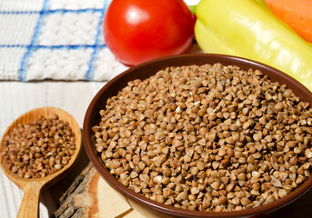 Buckwheat in a bowl, red pepper, carrots and onions on the board.