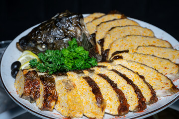 Stuffed fish on a plate with parsley, lemon and olives