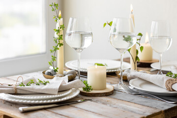 Rustic zero waste wedding decor with natural elements. Wooden table, candles, linen napkins, branches with green leaves. Eco-friendly decoration for the special dinner. Romantic and cozy place