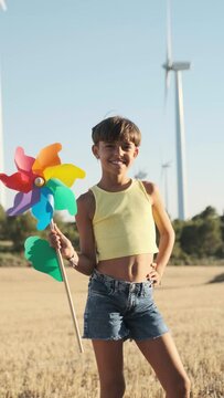 young activist woman with a toy windmill at a wind farm - future proofing concept