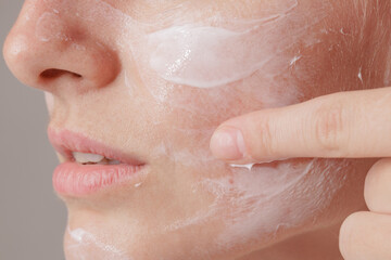 Fototapeta premium young woman applying moisturizer