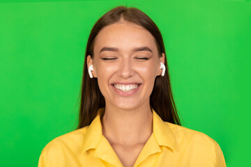 Woman Listening To Music With Earbuds Closing Eyes, Green Background