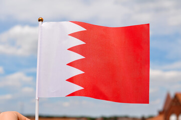 close up of national flag of bahrain on blue sky background ,red and white color