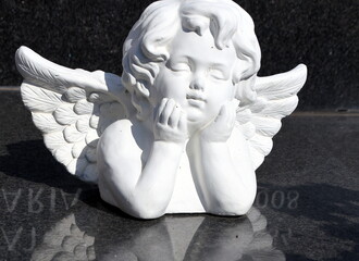 Kleiner, weißer Engel auf einer Grabplatte
