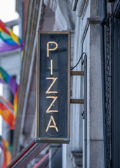 old neon pizza sign outside takeaway in city