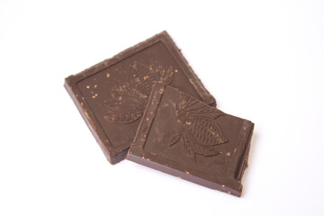 two cubes of dark chocolate lie on a white background