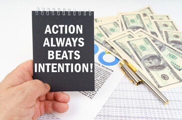 In the man's hand is a notepad with the inscription - ACTION ALWAYS BEATS INTENTION, in the background a pen and dollars