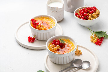 Creme brulee, cream brulee, burnt cream with currant in ramekins. Traditional french vanilla cream dessert with caramelised sugar on top. Homemade dessert with berries. Copy space. Selective focus.