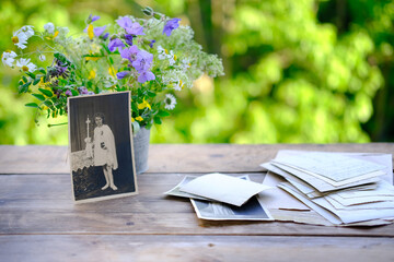 old vintage photographs, bouquet of wild flowers on table wooden table in garden, beautiful blurred...