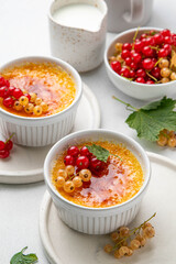 Creme brulee, cream brulee, burnt cream with currant in ramekins. Traditional french vanilla cream dessert with caramelised sugar on top. Homemade dessert decorated berries. Selective focus.