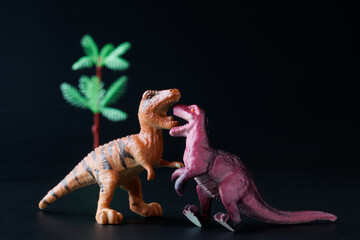 Toy dinosaurs interact and communicate on a dark background. The concept of studying history, the...