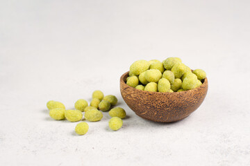 Pile of green wasabi coated peanuts in a bowl, spicy snack, oriental food
