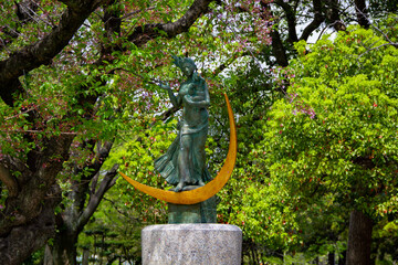 statue commemorating victims of nuclear war in Hiroshima among trees