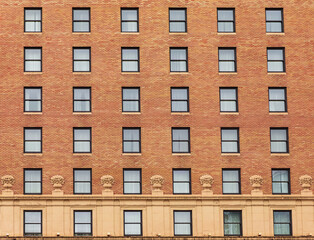 Many windows in row on facade of urban apartment building. Brick building.