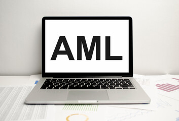 words AML Anti-Money Laundering on laptop display and charts