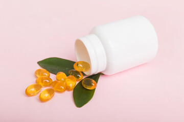 Omega-3 capsules lie in white bottle on a table background. Fish oil tablets top view. Biologically...