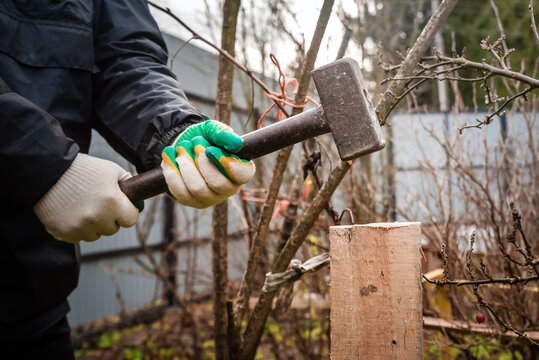photo of the hands of a man hammering a board with a sledgehammer into the ground