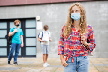 Portrait of teenage girl in face mask for disease protection walking after lessons at sunny day...