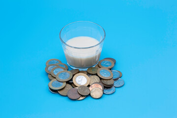 small glass of milk with coins around