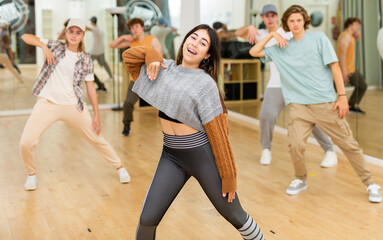Obraz premium Portrait of expressive teen girl krump dancer in choreographic studio with dancing teenagers in background.