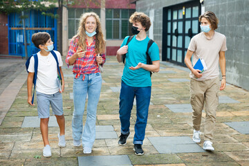 Group of positive cheerful teenagers hanging out on streets of city on summer day