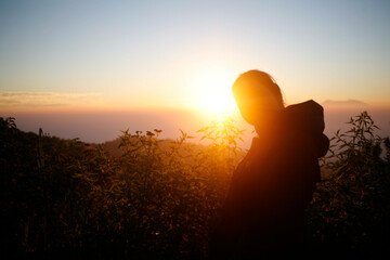 silhouette of a young woman admiring the sunset over the mountain hill