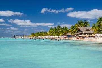 People swimming near white sand beach with umbrellas, bungalow bar and cocos palms, turquoise caribbean sea, Isla Mujeres island, Caribbean Sea, Cancun, Yucatan, Mexico