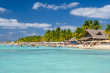 People swimming near white sand beach with umbrellas, bungalow bar and cocos palms, turquoise caribbean sea, Isla Mujeres island, Caribbean Sea, Cancun, Yucatan, Mexico